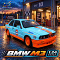 Light blue and orange BMW M3 1:24 RC diecast car, front three-quarter view in an illustrative racing garage